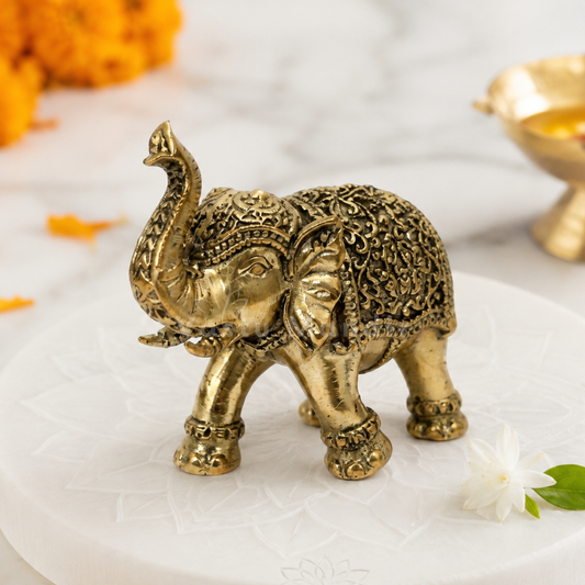 2-inch royal brass elephant figurine on a white surface with flowers and a bowl in the background