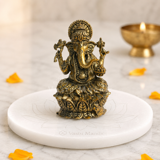 Brass Ganesha idol on lotus base front view on a sacred white pedestal with floral accents