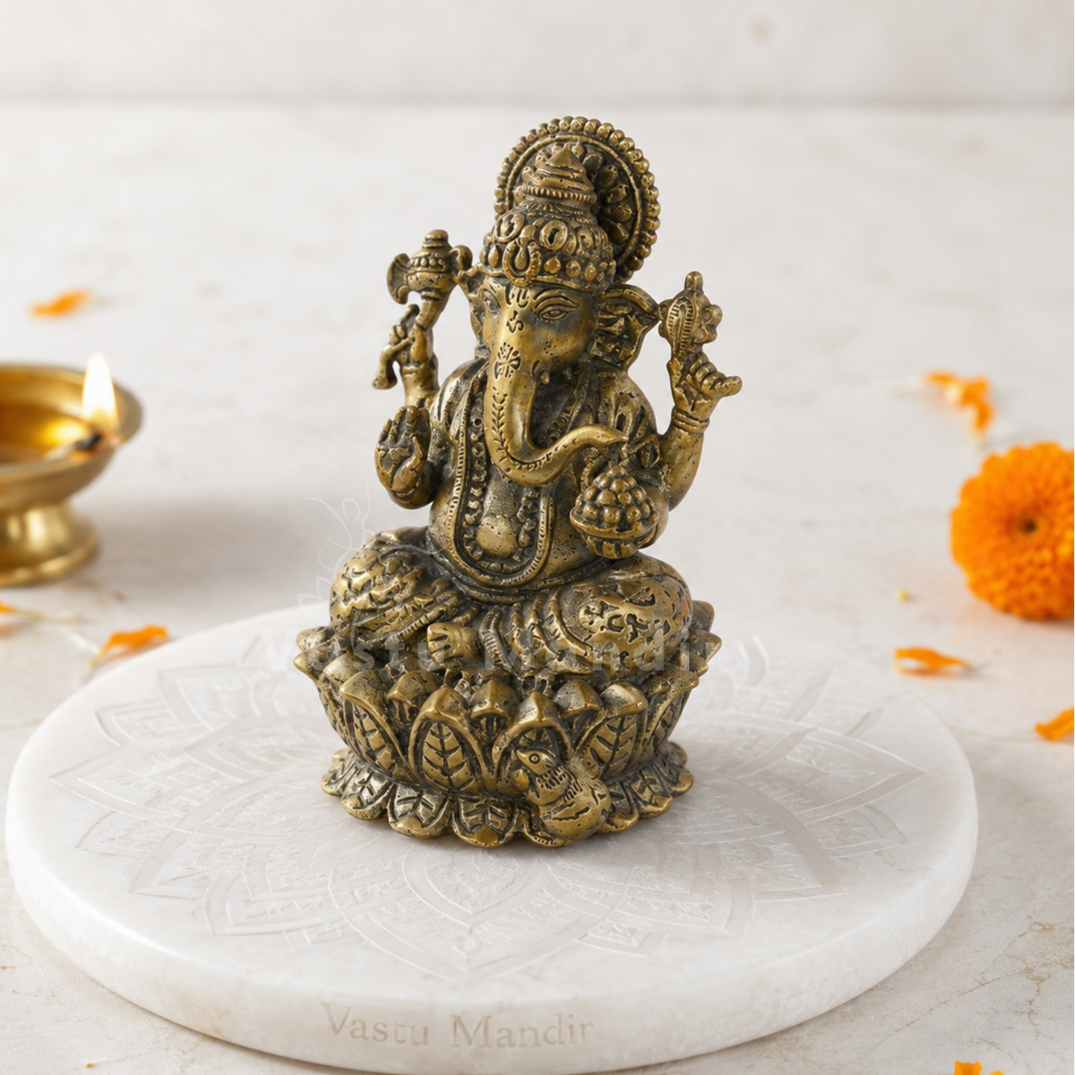 Brass Ganesha idol on lotus base displayed in a home temple setting