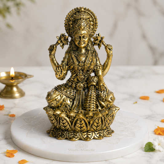 Brass Goddess Lakshmi idol front view on a sacred white pedestal with floral accents