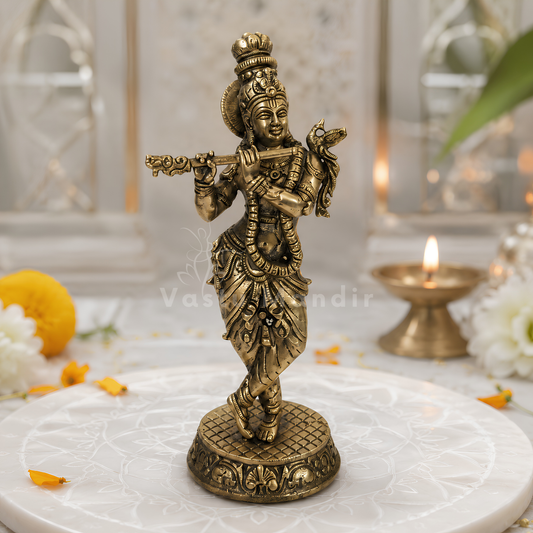 Brass Lord Krishna idol playing the flute on a sacred white pedestal with floral accents