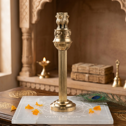 Brass Ashoka Pillar idol displayed in a carved wooden interior setting