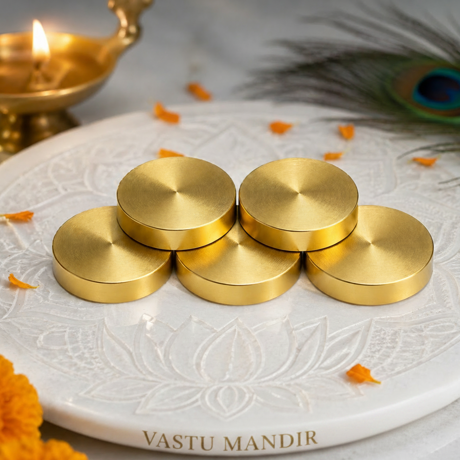Brass Vastu Coin on a decorative white plate with a peacock feather and decorations.