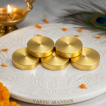 Brass Vastu Coin on a decorative white plate with a peacock feather and decorations.