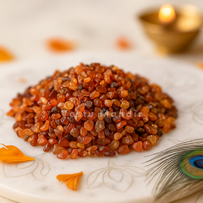 Stack of Carnelian stones on a decorative plate with a peacock feather and candle in the background.