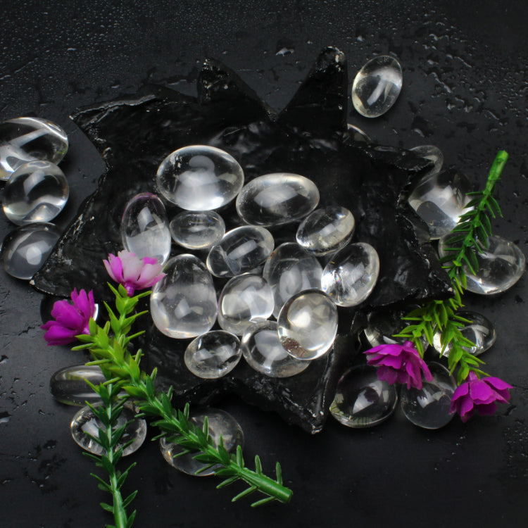 Clear quartz tumbled stones arranged against a dark background for a close product view