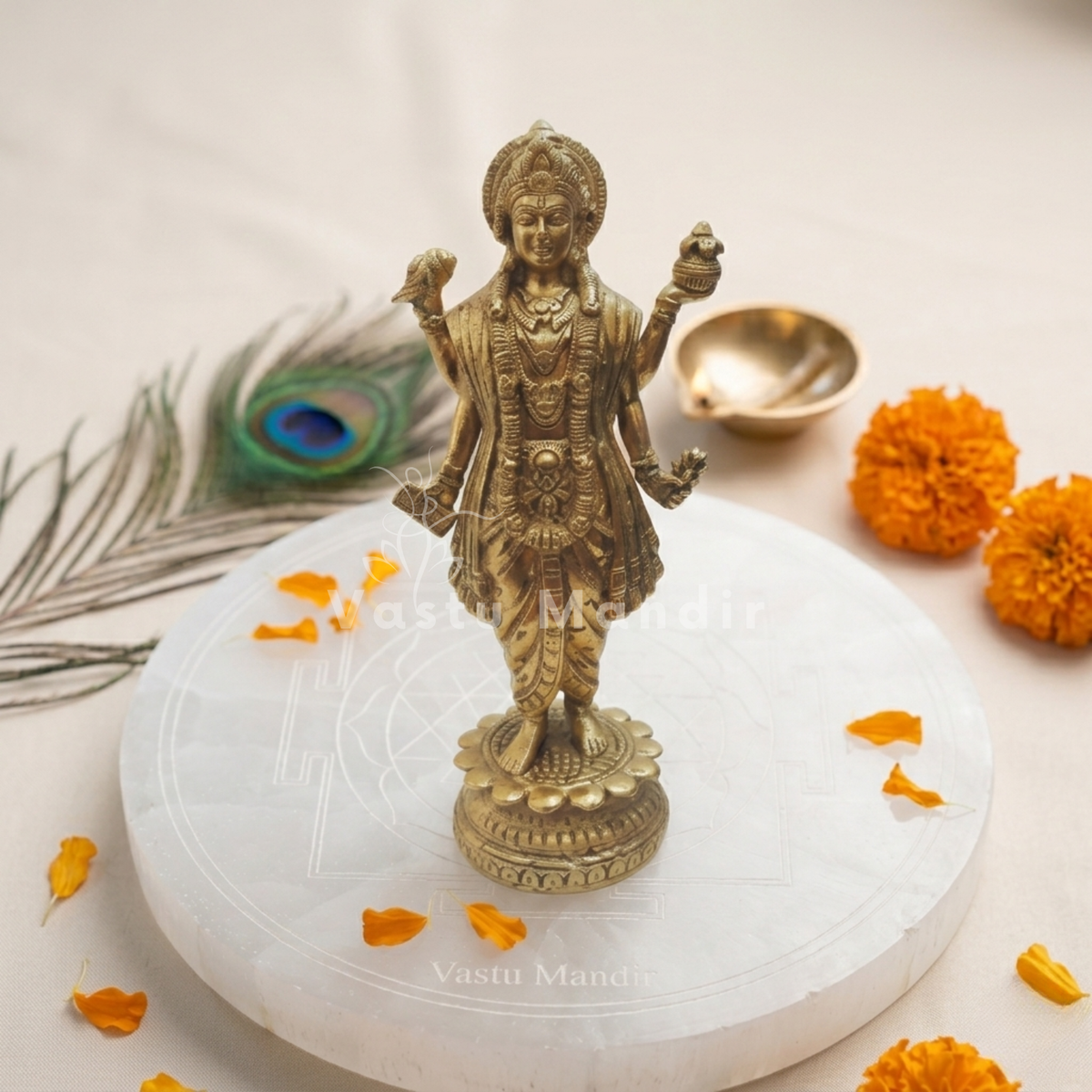 Brass Dhanvantri idol on a sacred white pedestal with marigold petals and peacock feather