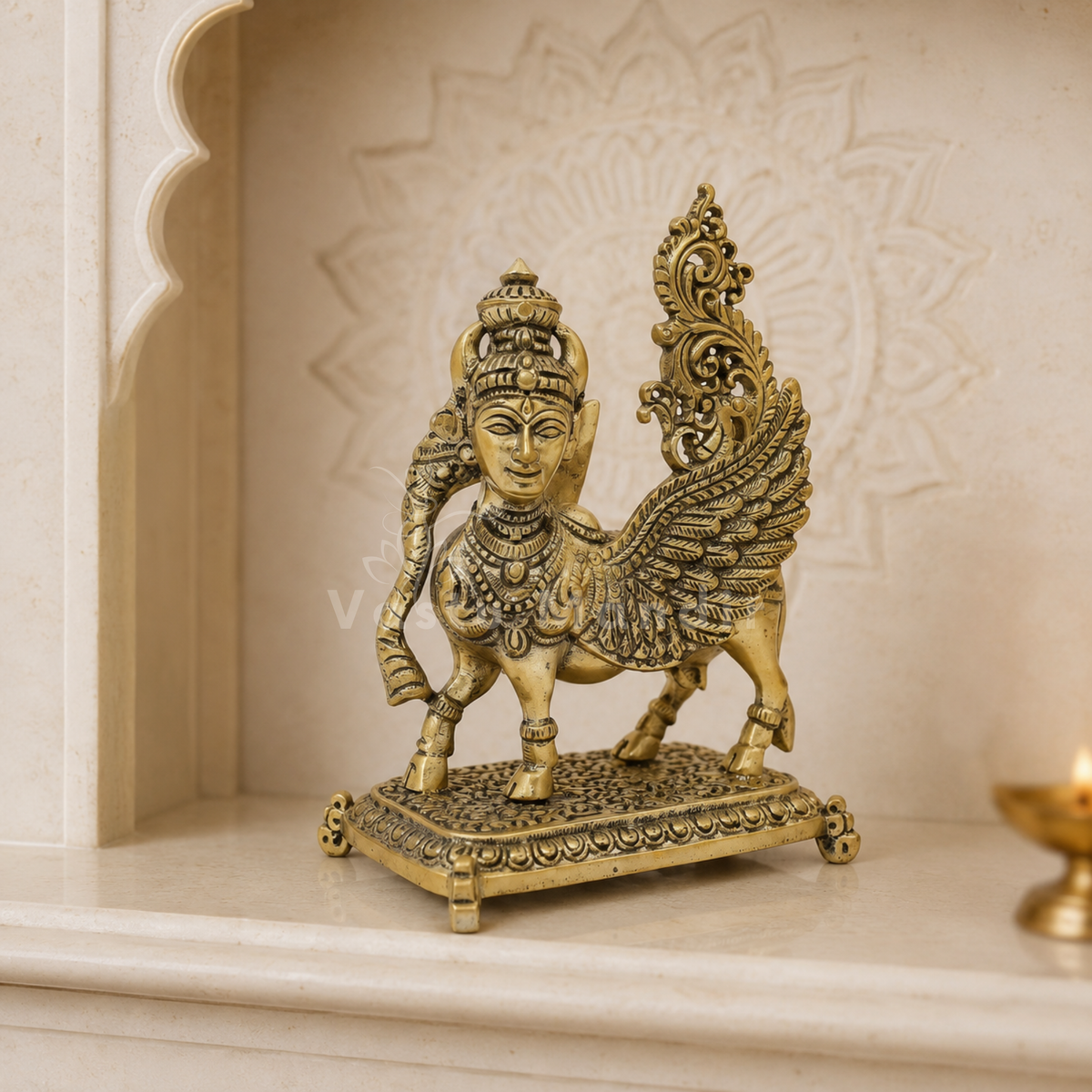 Flying Kamdhenu cow brass idol displayed on a white shelf in a neutral interior