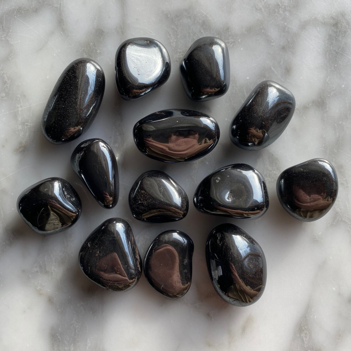 Hematite tumbled stones spread on a wooden surface in natural light