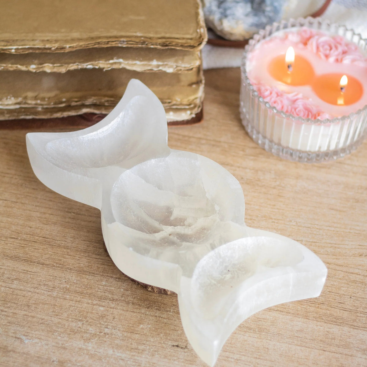 Triple moon selenite charging bowl presented in a second hand-held view