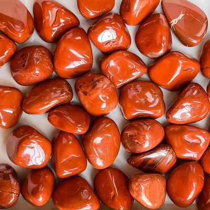 Macro view of red jasper tumbled stones showing polished surfaces, colour variation and natural markings