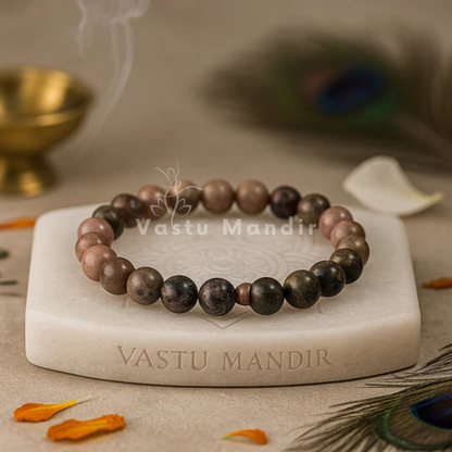 Natural Rhodonite Crystal Bracelet arranged on a square marble riser beside a brass diya