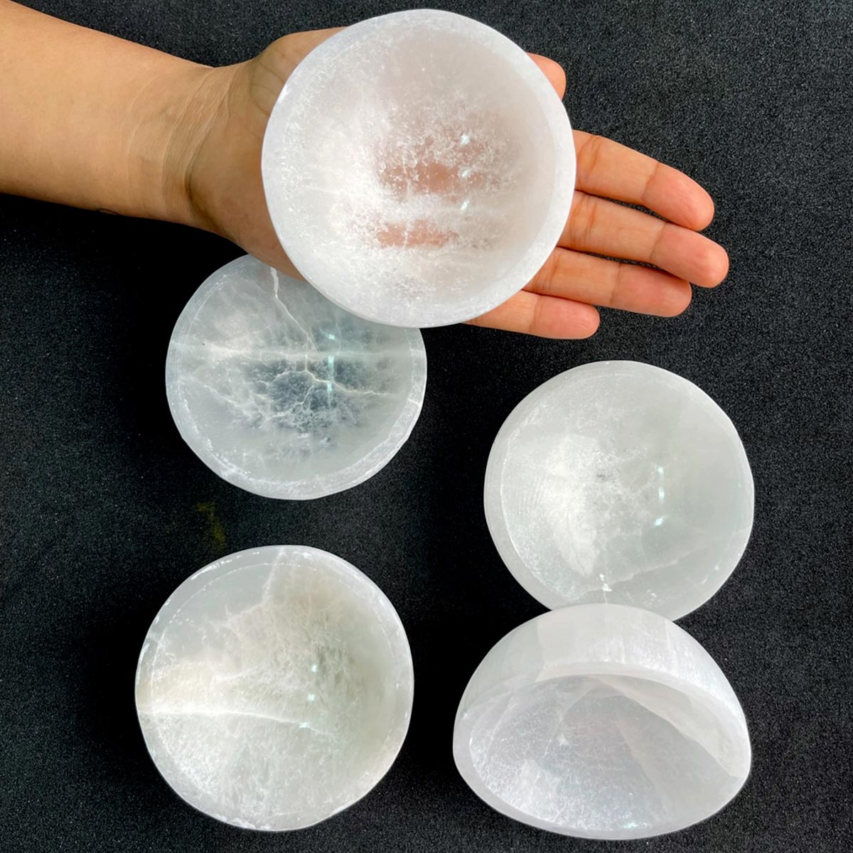 Round selenite charging bowl arranged in a warm low-light product setting