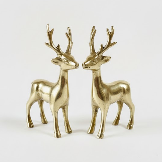 Two brass deer figurines on a white background
