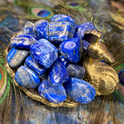 Lapis lazuli stones arranged on a woven mat beside folded gold fabric