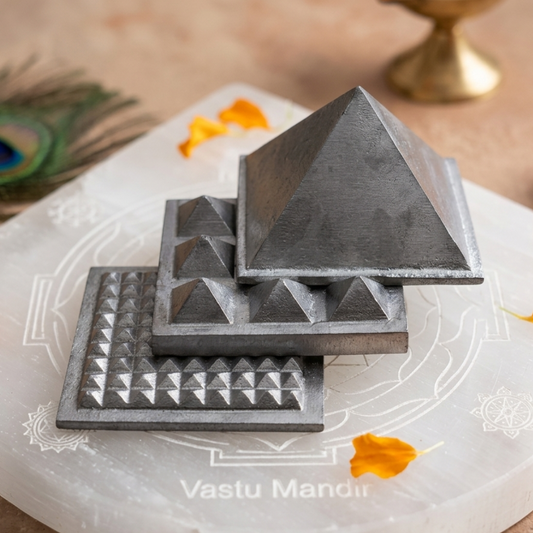 3-layer lead Vastu pyramid displayed on a white sacred plate with marigold petals