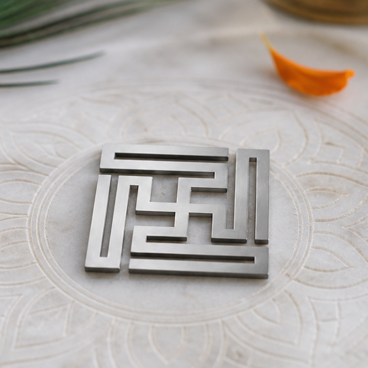 Metal maze sculpture on a marble surface with peacock feather and lit candle