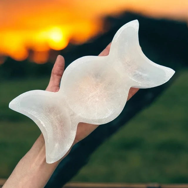 Triple moon selenite charging bowl arranged in a warm low-light product setting