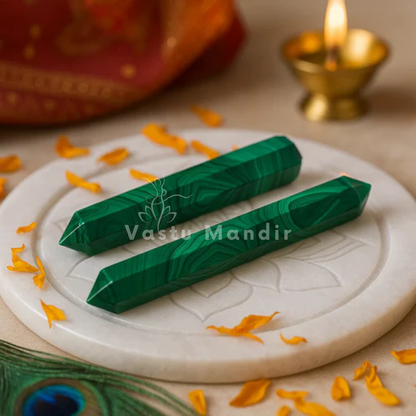 Two green malachite crystal pencils displayed on a white plate with marigold petals