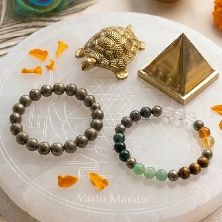 Wealth Activation Set with Two beaded bracelets on a white plate with decorative elements including a turtle, pyramid, and peacock feather.