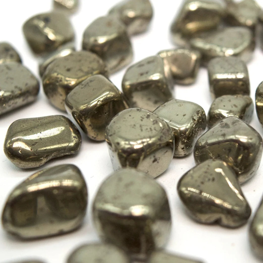 Close-up of pyrite tumbled stones on a clean white background showing natural colour and texture