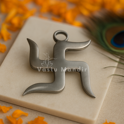 Metallic Swastika symbol on a beige surface with orange flowers and a peacock feather in the background.