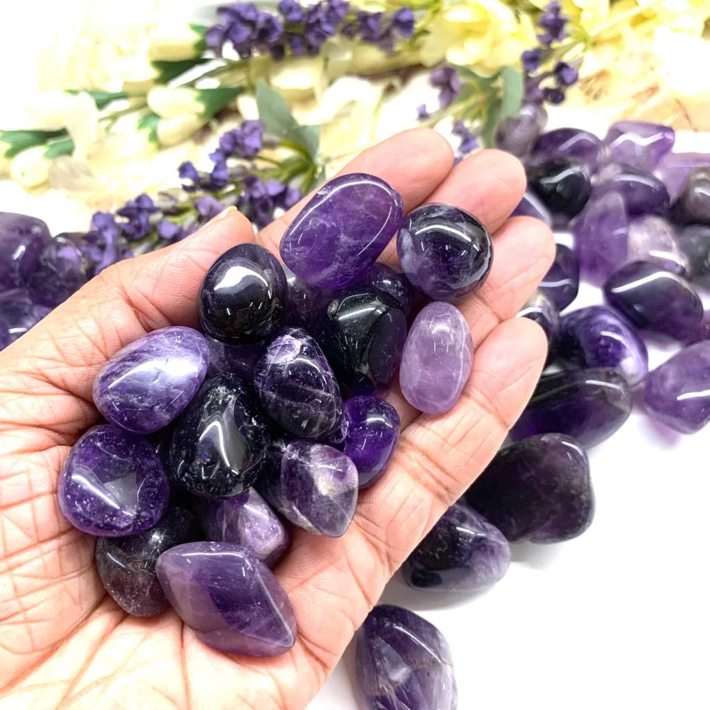 Hand holding several amethyst stones outdoors to show natural colour, scale and texture