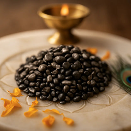 Angled view of pyrite crystal chips on a white plate with marigold petals and a peacock feather