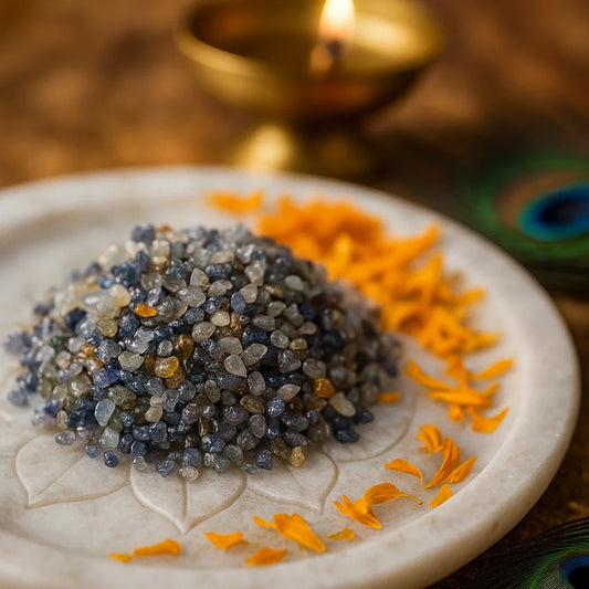Small blue-grey sapphire gemstone chips arranged on a white plate with marigold petals