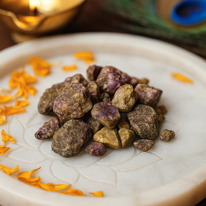 Close view of green and purple rough ruby zoisite stones on a decorated white plate