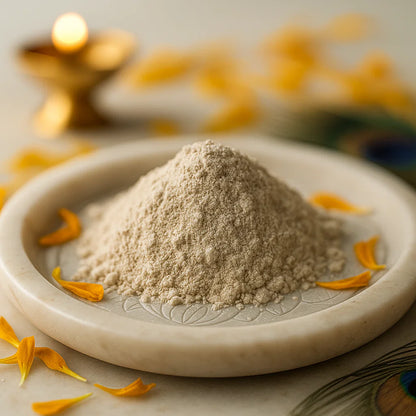 Muscovite mica crystal powder piled on a white plate with marigold petals and a softly lit diya