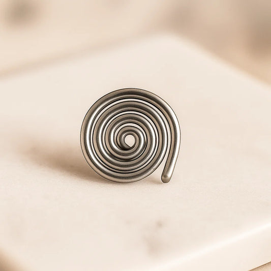 Iron spiral Vastu spring displayed upright on a pale stone block