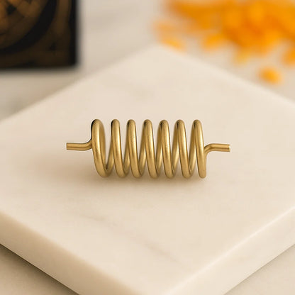 Brass Vastu spring shown horizontally on a pale stone block