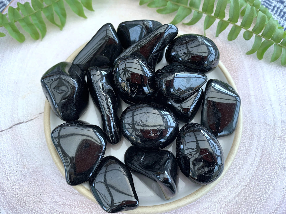 Black tourmaline tumbled stones arranged in a shallow white dish