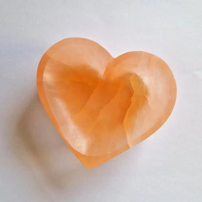 Orange heart selenite charging bowl arranged in a styled spiritual setting