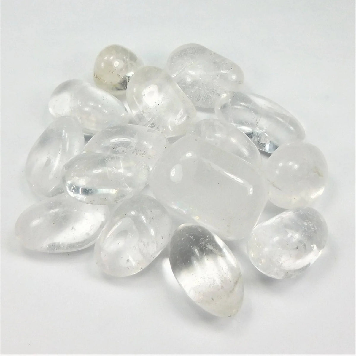 Small translucent clear quartz stones spread on a white background