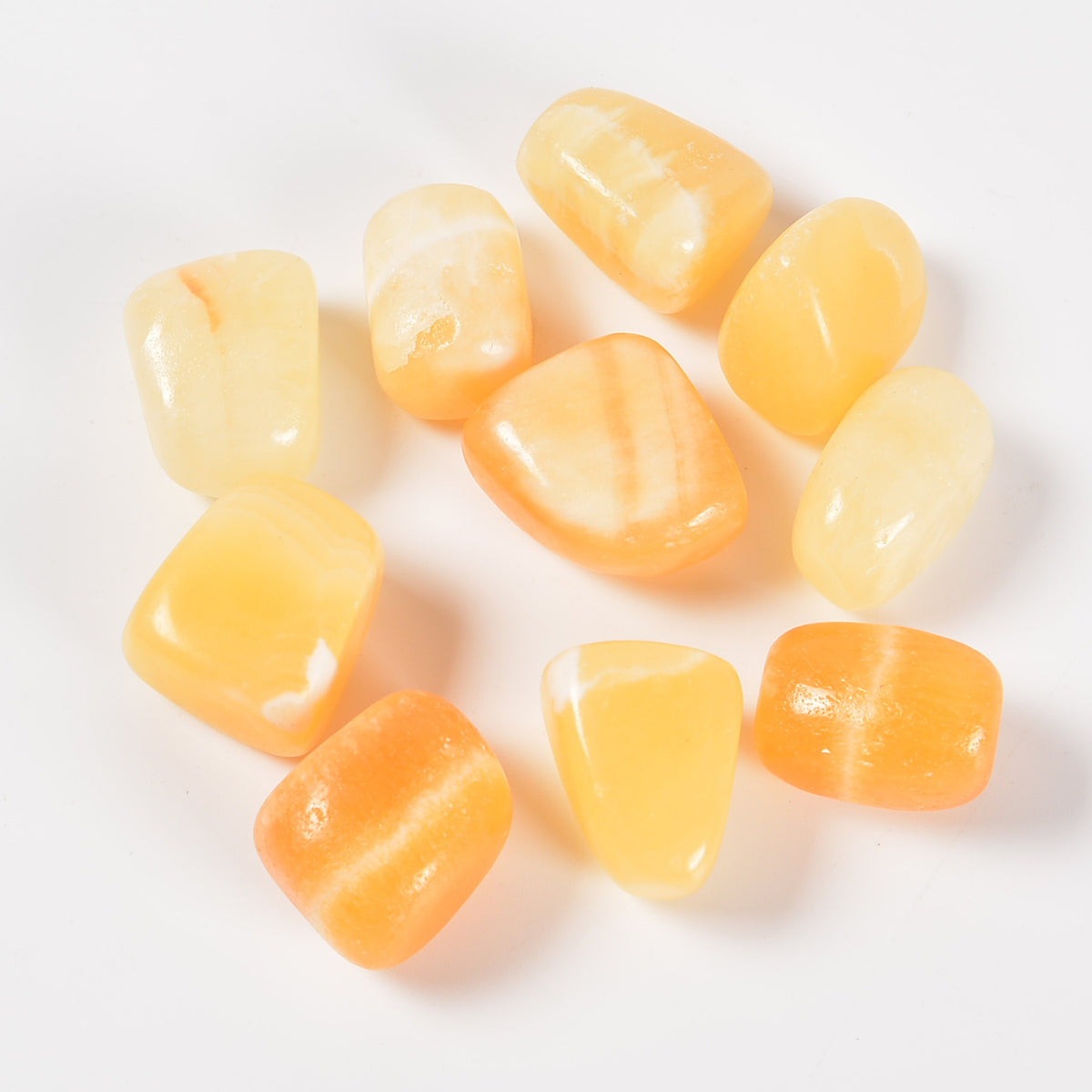 Close-up of yellow jade tumbled stones on a clean white background showing natural colour and texture