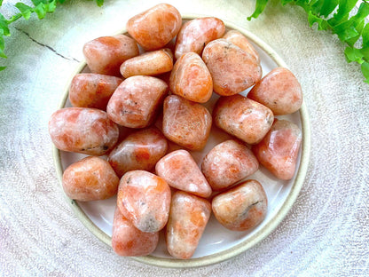 Sunstone tumbled stones displayed in a small bowl with a neutral background