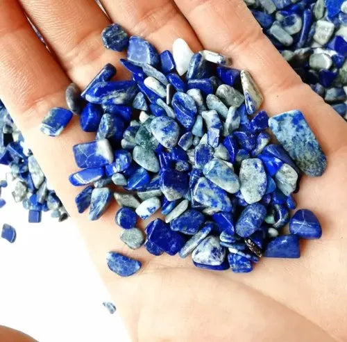 Hand holding a pile of small lapis lazuli chips to show colour and scale