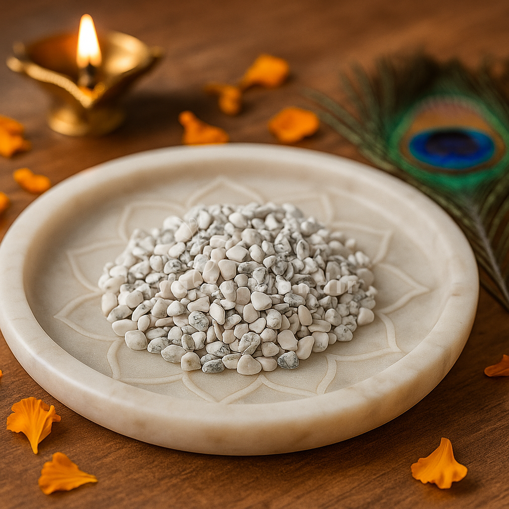 Angled view of howlite crystal chips on a white plate with marigold petals and a peacock feather
