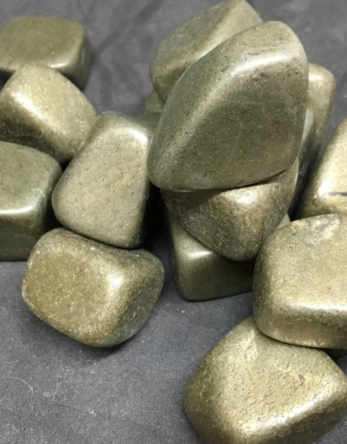 Macro view of pyrite tumbled stones showing polished surfaces, colour variation and natural markings