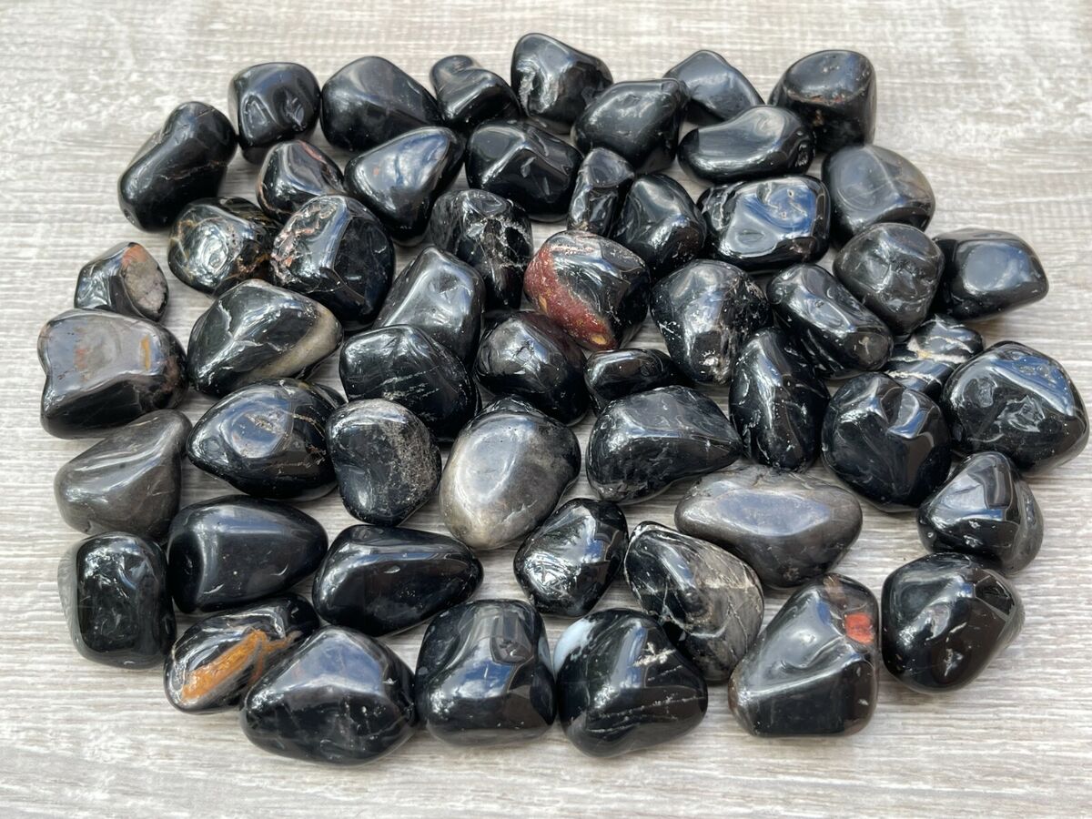 Small pile of black onyx tumbled stones arranged on a light woven fabric surface
