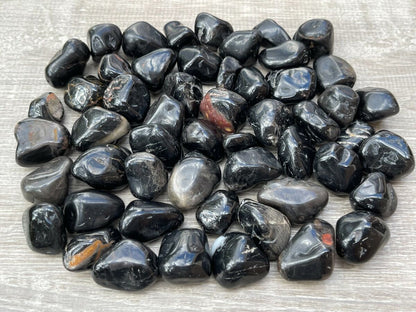Small pile of black onyx tumbled stones arranged on a light woven fabric surface