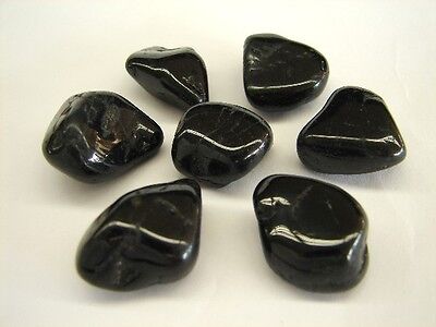 Seven polished black tourmaline stones arranged on a light background