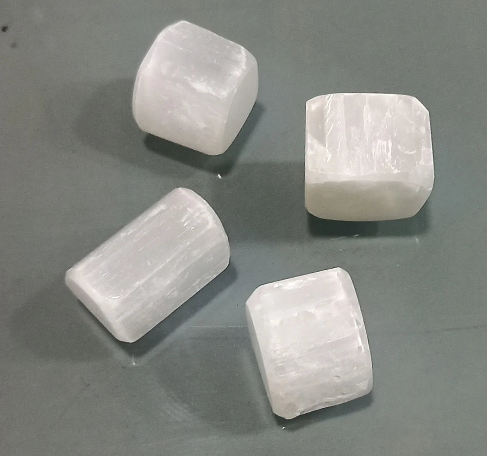 Three rectangular selenite blocks displayed on a neutral grey surface