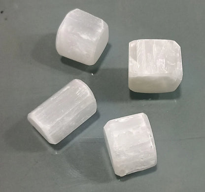Three rectangular selenite blocks displayed on a neutral grey surface