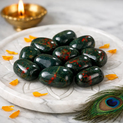 Natural bloodstone tumbled stones arranged in a warm low-light product setting