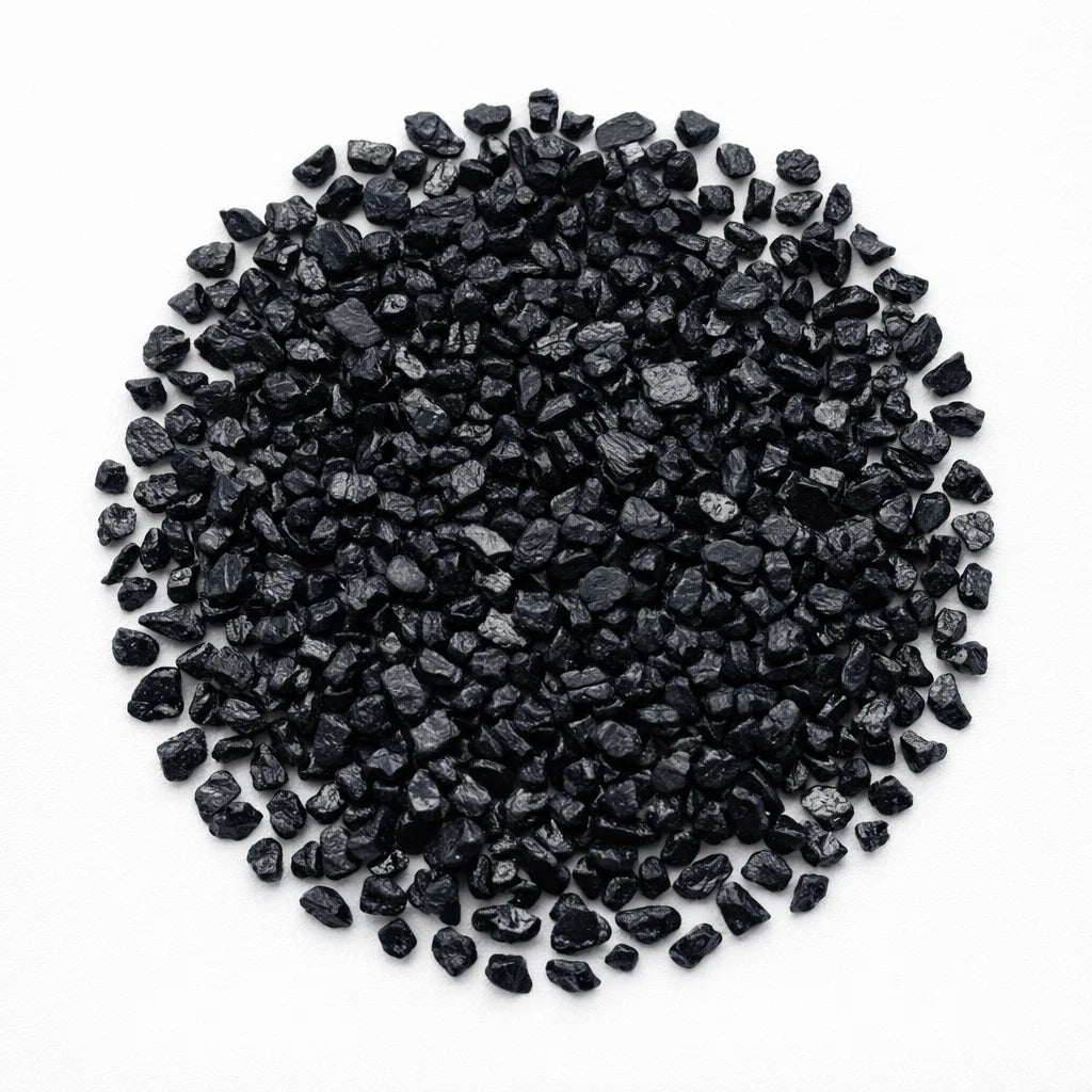 Close-up of black tourmaline crystal chips on a clean white background showing natural colour and texture