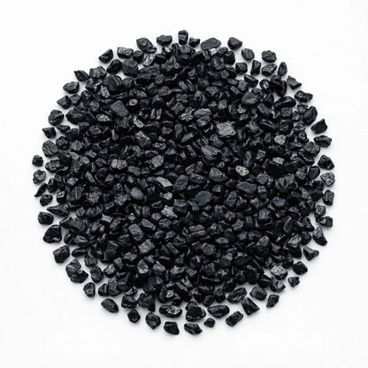 Close-up of black tourmaline crystal chips on a clean white background showing natural colour and texture