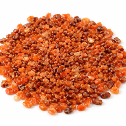 Close-up of carnelian crystal chips on a clean white background showing natural colour and texture